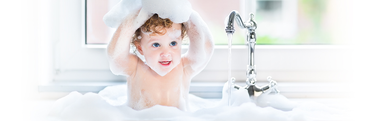 un petit garçon prend un bain, il est entouré de mousse