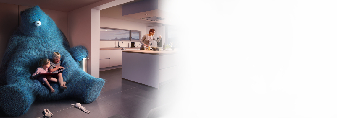 Une dame cuisine pendant que ses enfants lisent un livre, confortablement installés sur un ours bleu 